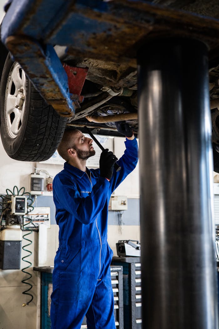 Services A Mechanic In Blue Coverall Working Under A Vehicle 8986068